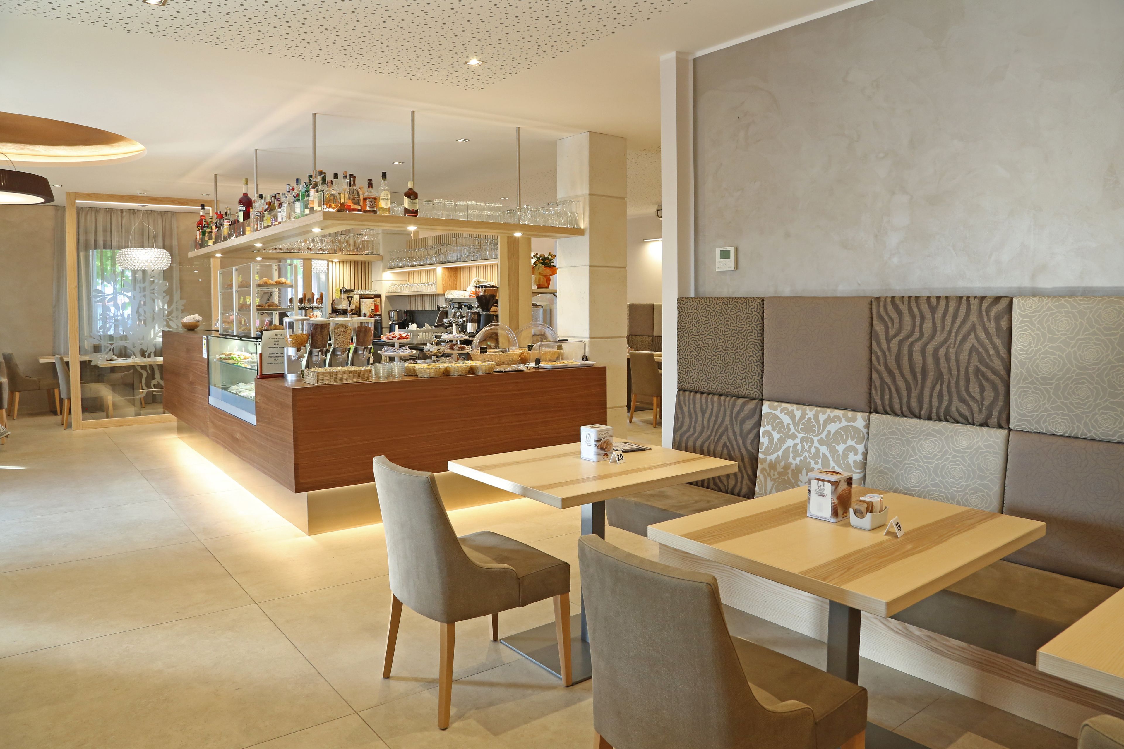 Un restaurante moderno con zona de bar, asientos y una pared decorativa.