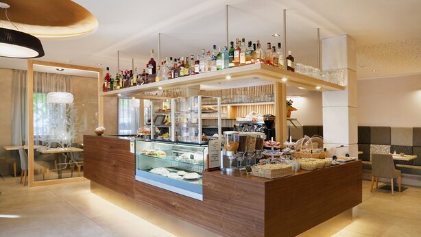 Een moderne bar met een houten toonbank, glazen vitrines en diverse flessen en glazen.