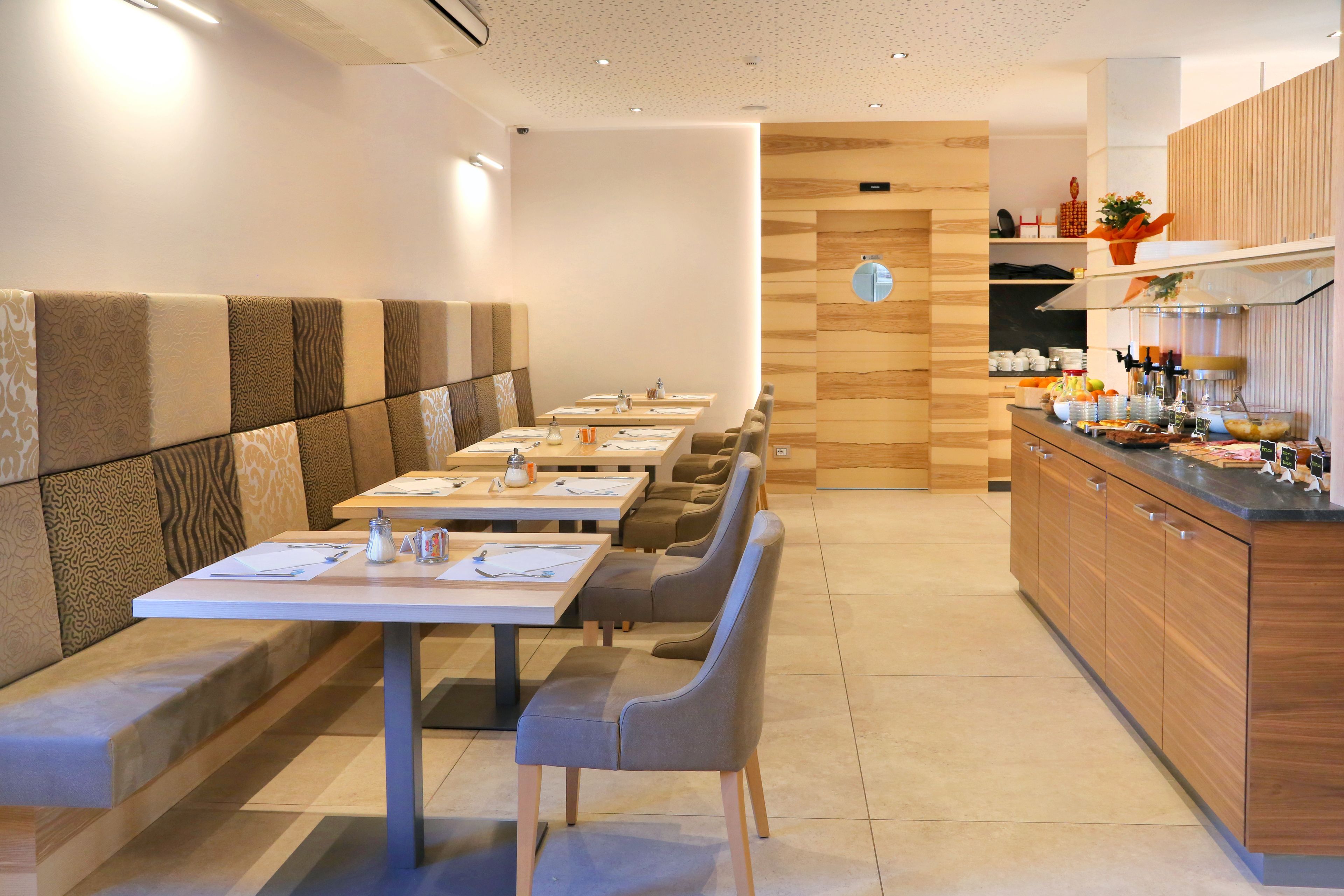 A modern restaurant with a long counter, booths, and a kitchen area.