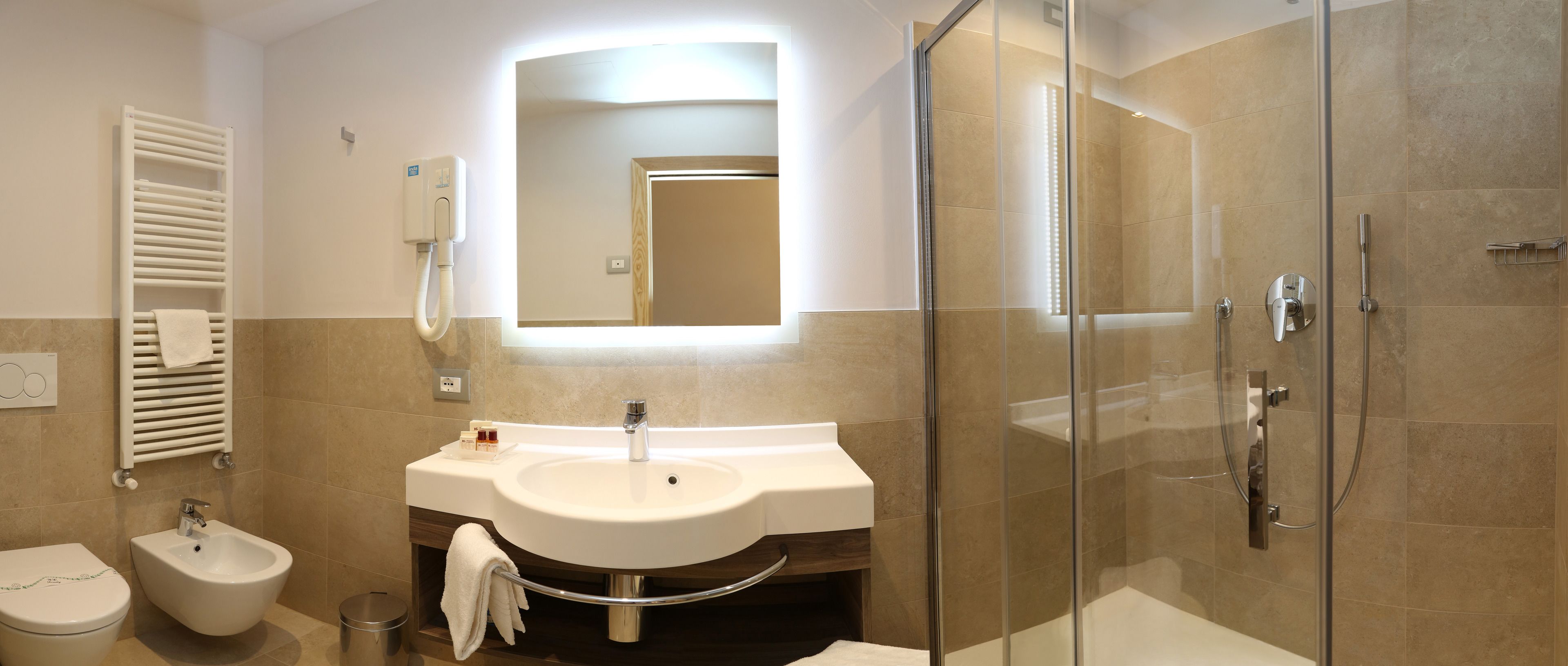 Une salle de bain moderne avec une douche à parois de verre, un lavabo avec un miroir au-dessus et un bidet.