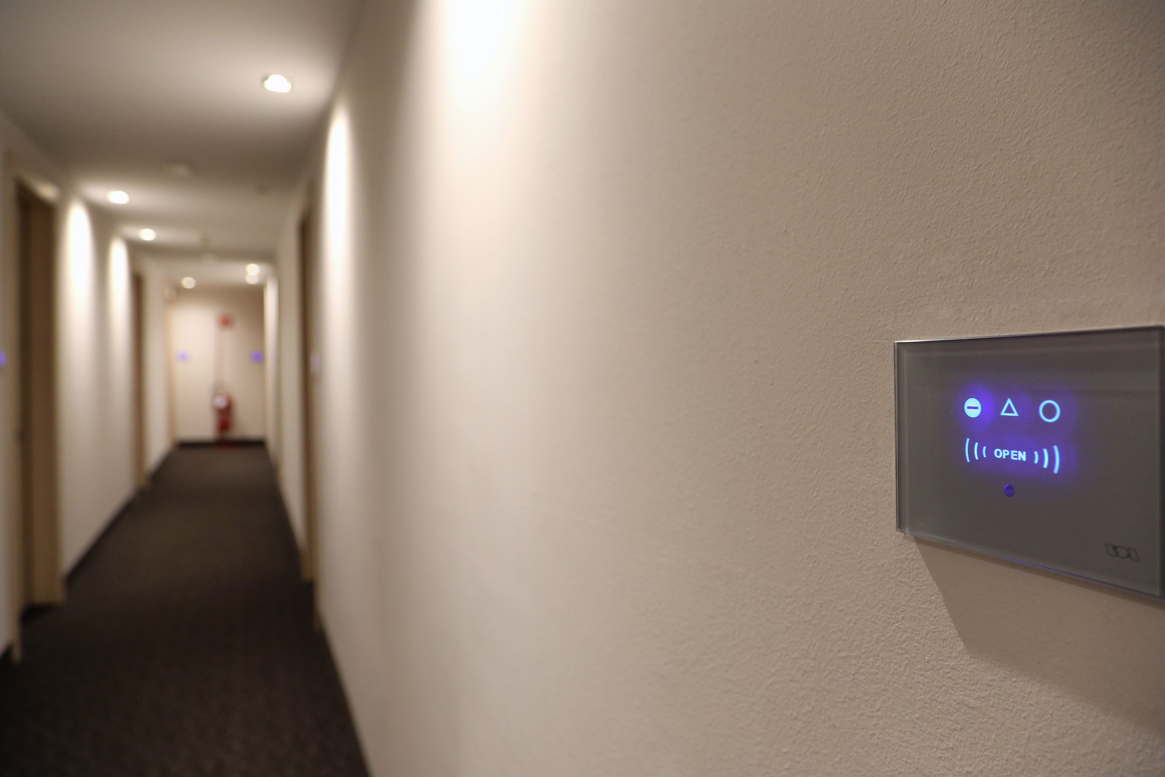 Un pasillo con un panel de control en la pared que muestra símbolos y la palabra 