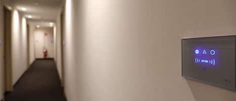 Un pasillo con un panel de control en la pared que muestra símbolos y la palabra