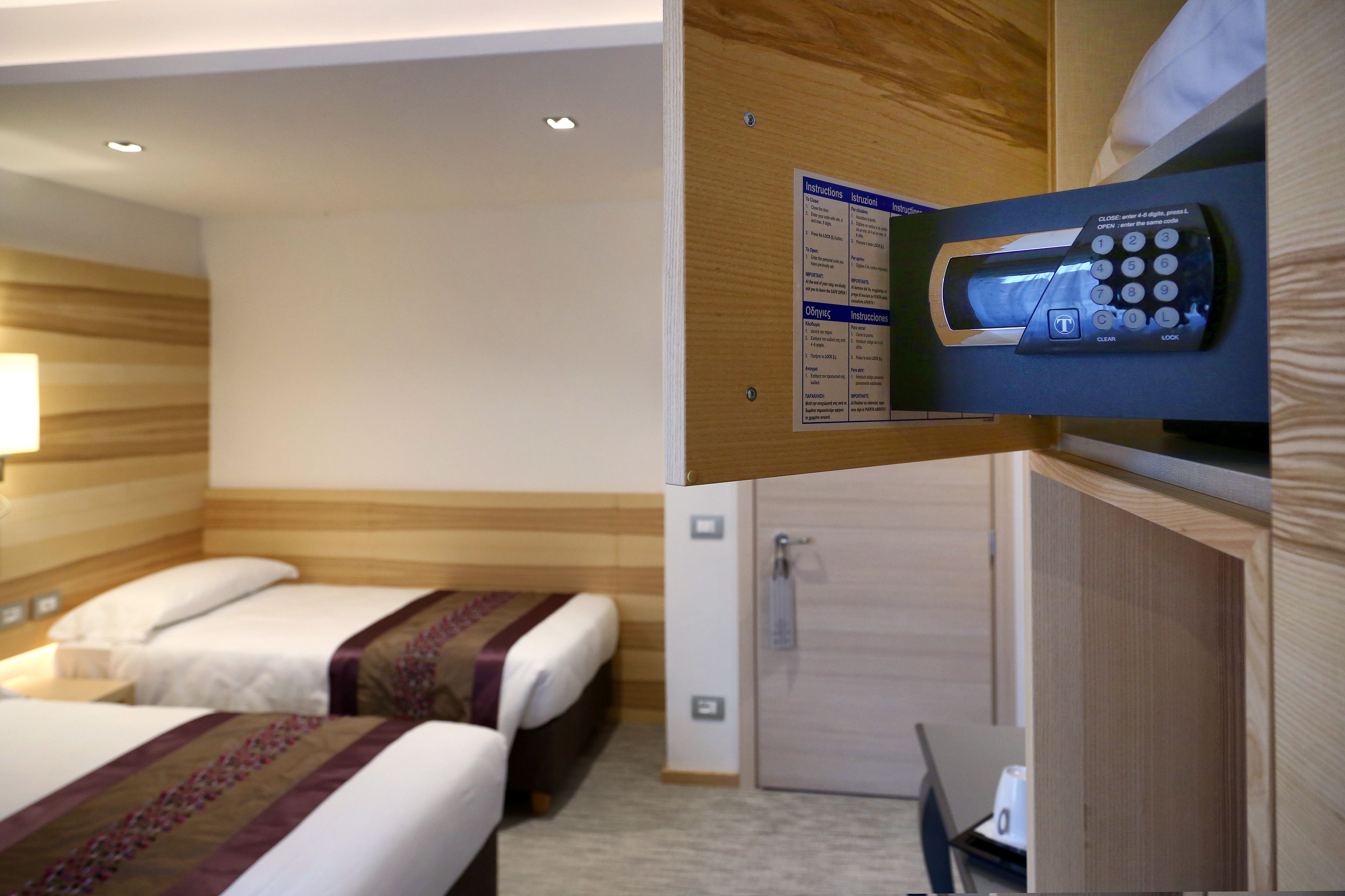 Habitación de hotel con dos camas, un escritorio y una puerta con cerradura.