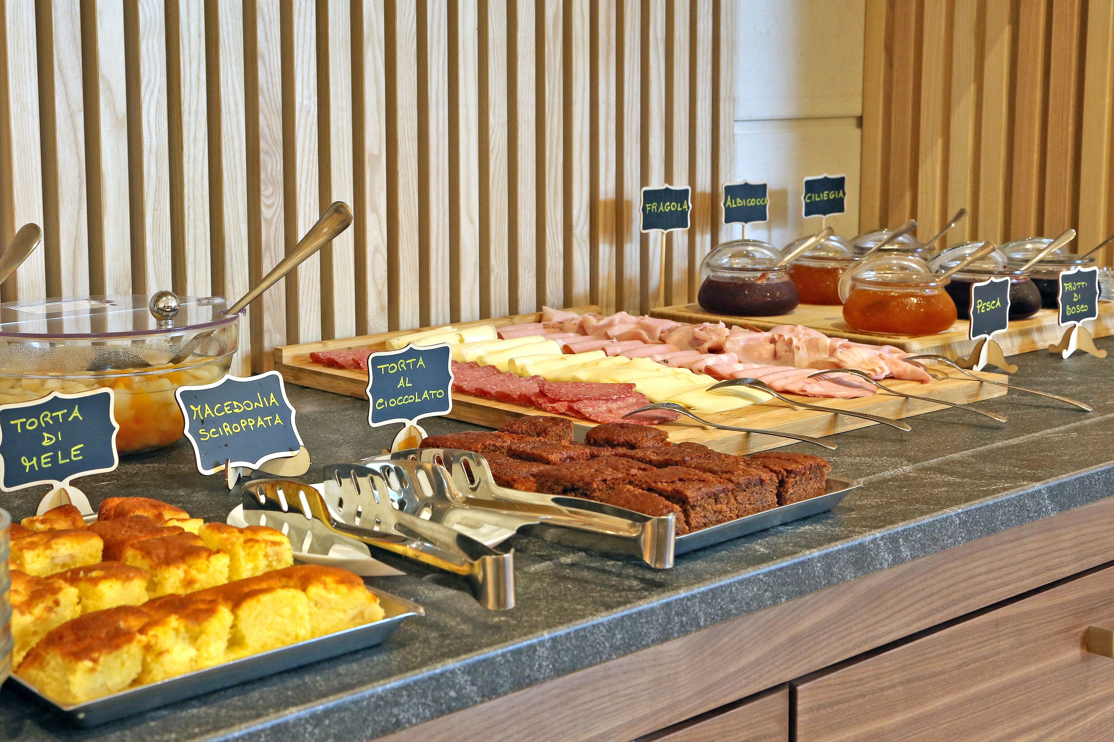 A buffet with various food items including torta, macaroni, and different types of cheese.