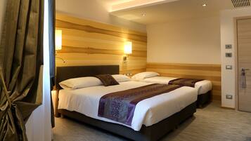 Habitación de hotel con una cama grande, dos mesitas de noche, un cabecero, una lámpara de pared y una puerta.