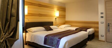 Habitación de hotel con una cama grande, dos mesitas de noche, un cabecero, una lámpara de pared y una puerta.