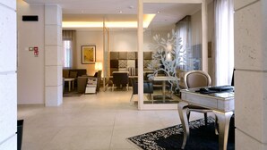 Een moderne hotelkamer met een zithoek, een bureau met stoel, en een groot raam met gordijnen.