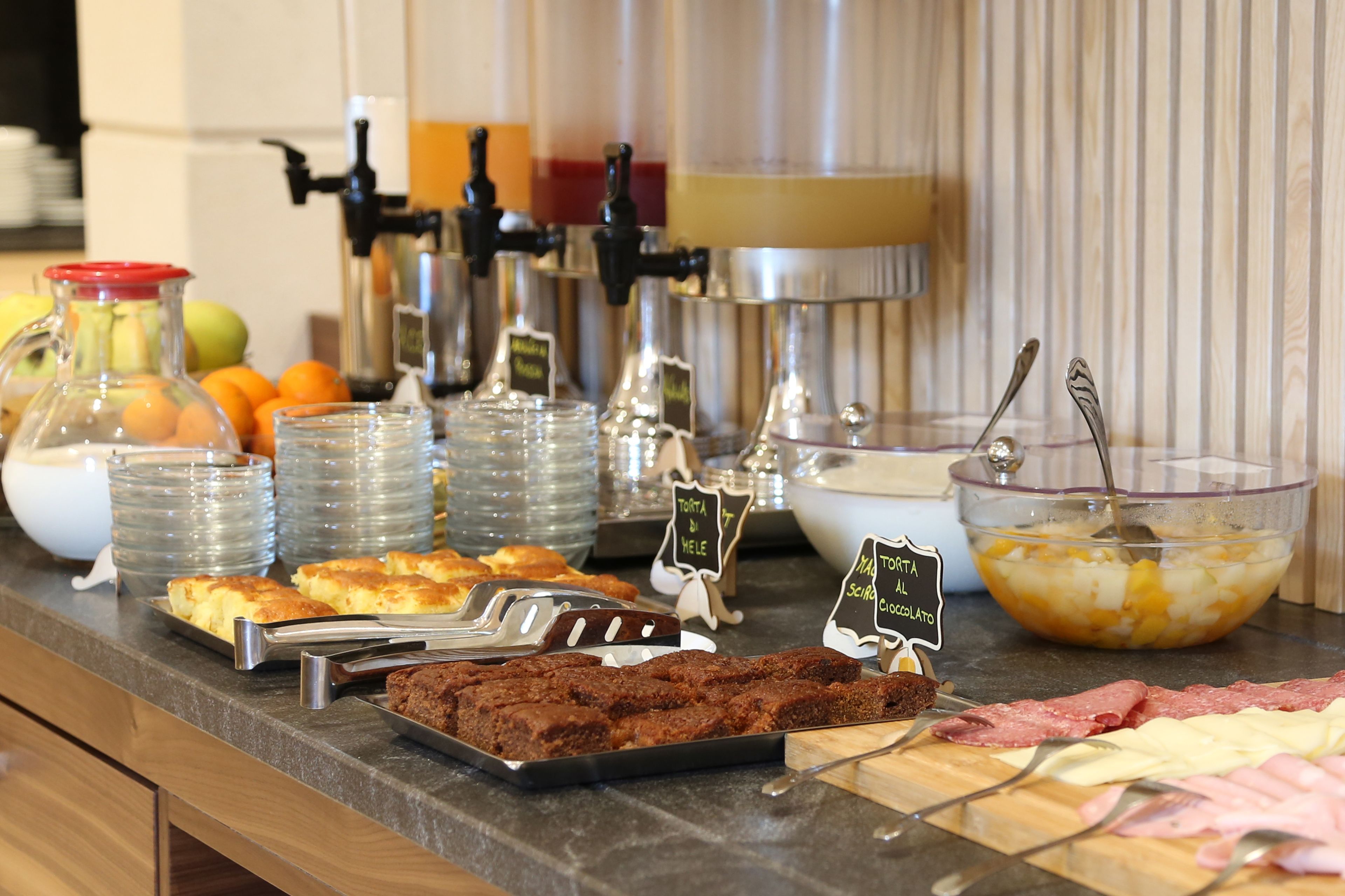 A buffet with various food items including fruits, bread, and meats.