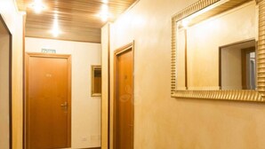 Un couloir avec des portes en bois et un miroir au mur.