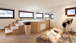A modern bathroom with a large bathtub, a mirror, and a sunlit window. - Hotel Montana (Pinzolo)