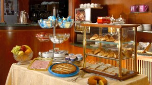 A breakfast buffet with various food items and a coffee machine. - Hotel Assisi (Rome)