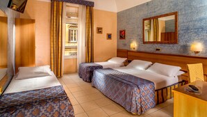 A hotel room with two beds, a wooden headboard, a mirror, and a small desk with a lamp. - Hotel Assisi (Rome)