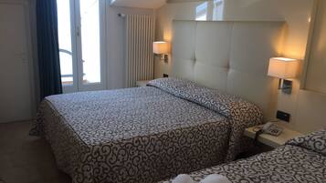 Habitación de hotel con una cama grande, dos mesitas de noche, una lámpara y un teléfono.