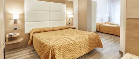 A hotel room with a large bed, a bedside table, a nightstand, and a mirror.
