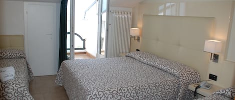 A hotel room with two beds, a balcony, and a telephone.
