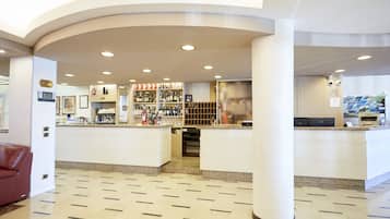 Un hall d’hôtel comprenant un comptoir d’accueil, un bar et un espace salon.