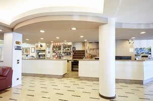 Un vestíbulo de hotel con una recepción, una zona de bar y un área de estar.