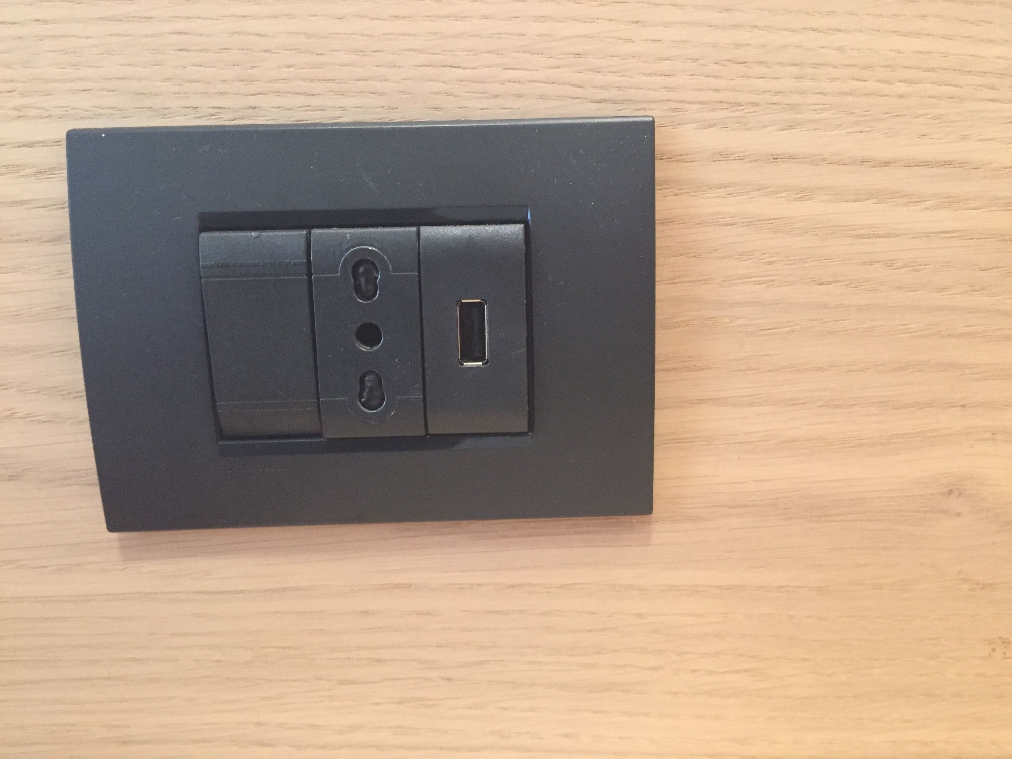 Eine schwarze Steckdose mit zwei Schaltern und einem USB-Anschluss auf einer Holzoberfläche.