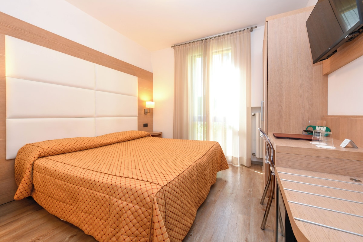 Una camera d'albergo con un letto grande, una scrivania e un televisore a parete.
