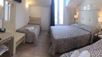 A hotel room with two beds, a desk, a chair, a telephone, and a bathroom with a shower and toilet.