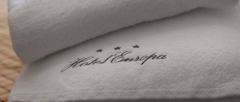 A neatly folded white towel with the text "Hotel Europa" on it, placed on a bed.
