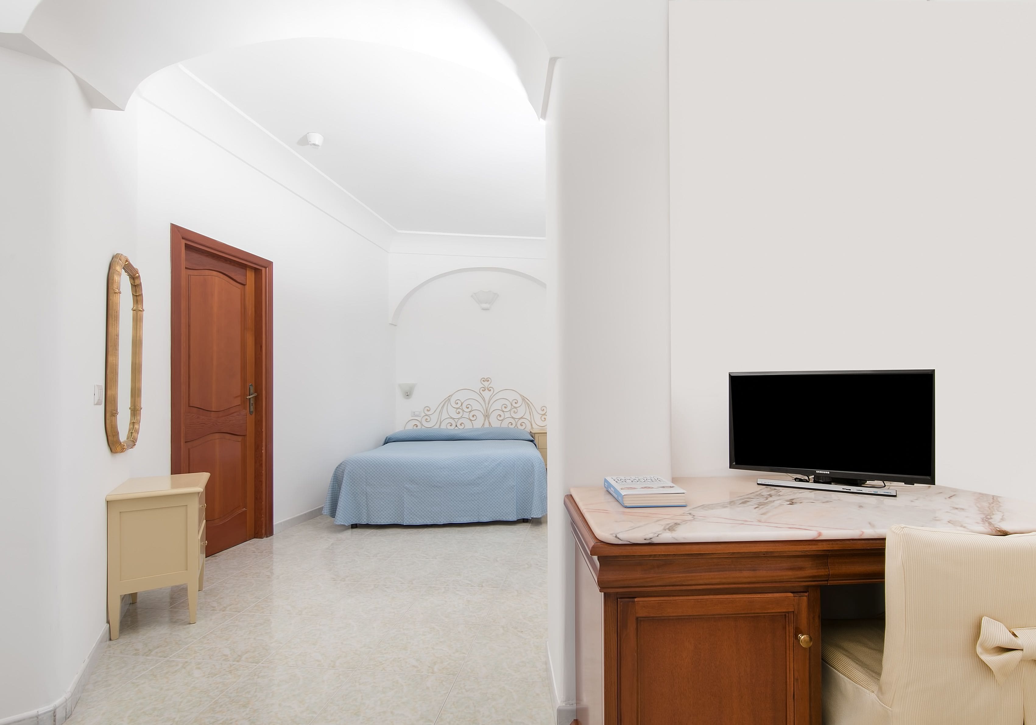 A bedroom with a bed, a TV, a desk, and a chair.