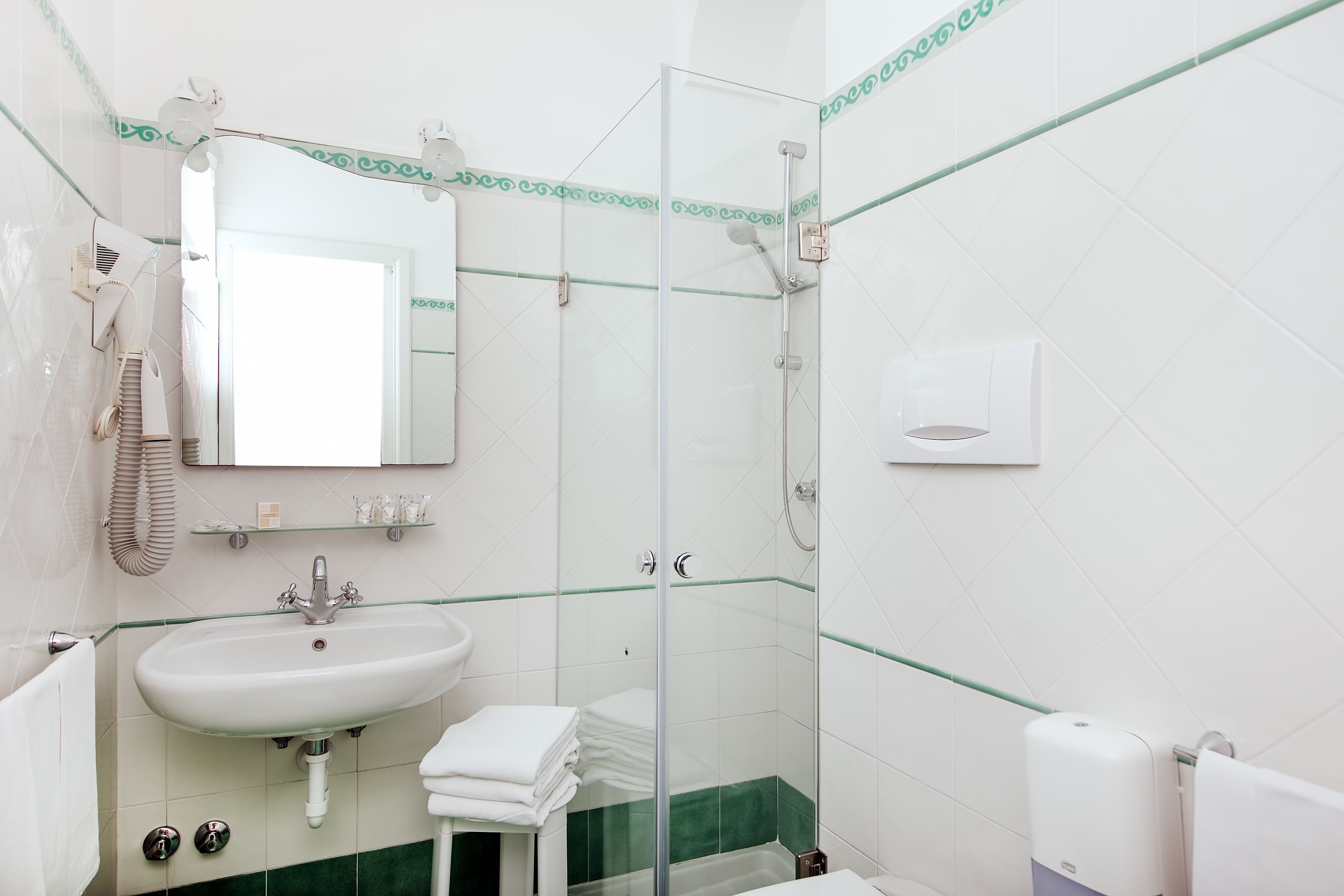 Casa de banho com cabine de duche envidraçada, lavatório com espelho e barra de toalhas.
