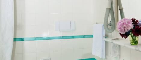 A bathroom with a sink, two urinals, a toilet, a shower curtain, and a mirror with a hairdryer.