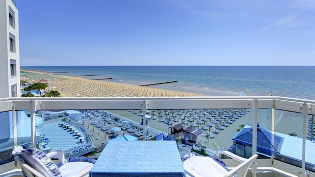 A balcony with a view of a beach and a pool area.