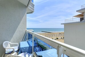 A balcony with a view of the beach, white chairs, and a table with a blue tablecloth. - Hotel Cavalieri Palace (Jesolo)