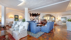 A spacious lobby with patterned sofas, a bar area, and a modern ceiling design.