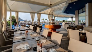 A restaurant with outdoor seating, a pool, and a view of the mountains.