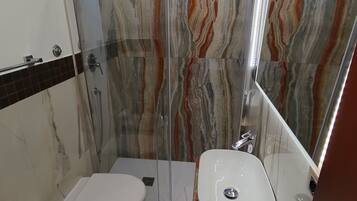 Un bagno moderno con doccia vetrata, toilette, bidet e lavandino.