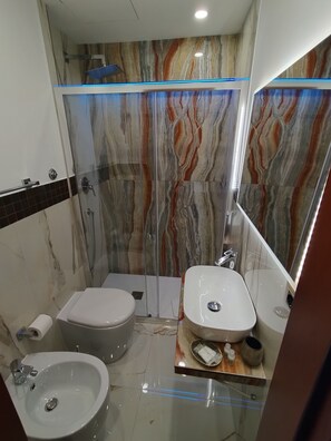 A modern bathroom with a glass-enclosed shower, a toilet, a bidet, and a sink. - Hotel Ercoli (Rome)