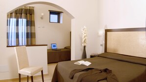 A hotel room with a bed, a desk with a laptop, a chair, a vase with flowers, and a window with curtains. - Hotel dei Mille (Rome)