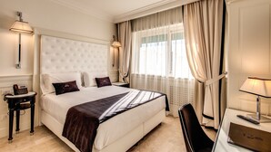 Una habitación de hotel con una cama grande, lámparas de noche, un escritorio con una computadora portátil y una silla.