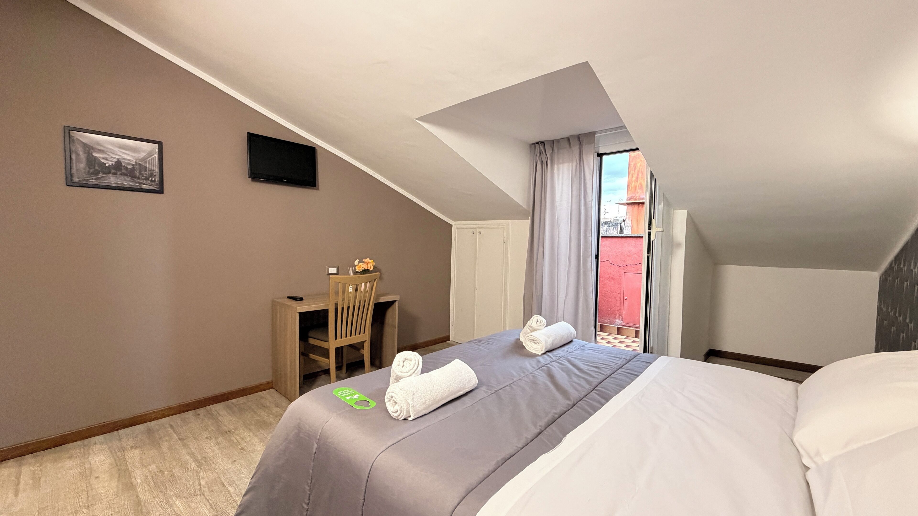 Een hotelkamer met een bed, een bureau, een stoel, een televisie en een raam met gordijnen.