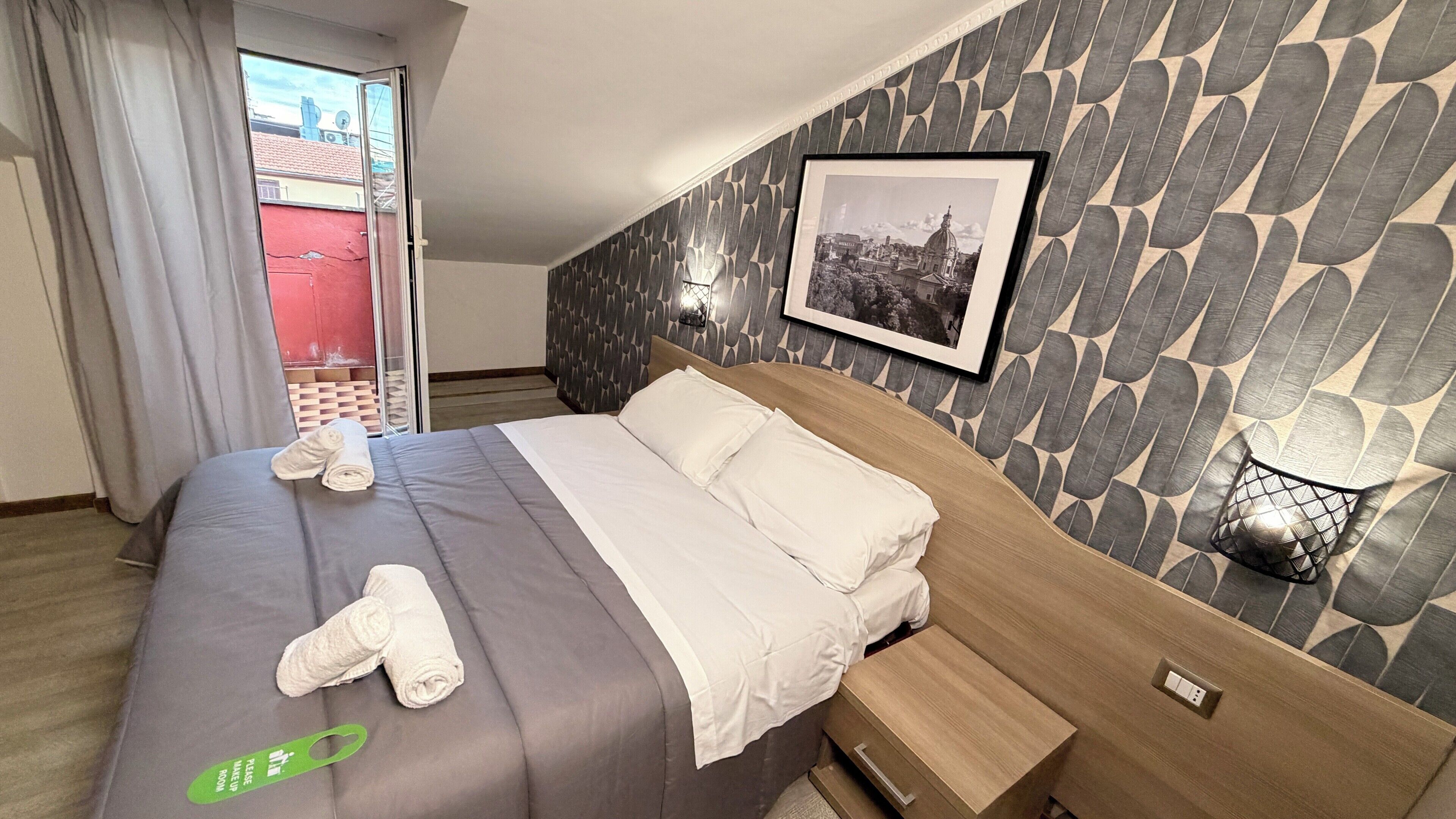 A hotel room with a bed, a green sign, a framed photo, and a patterned wall.