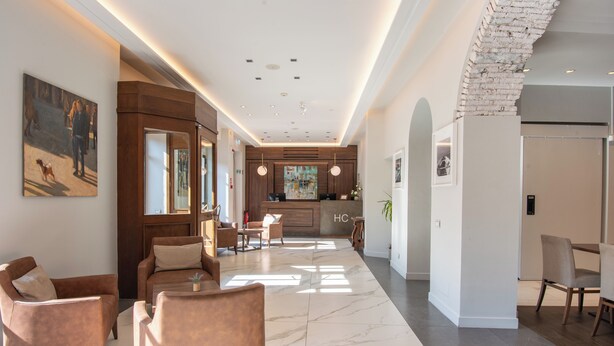 A modern hotel lobby with a marble floor, leather seating, a kitchen area, and a reception desk. - Hotel Centrale (Cernobbio)