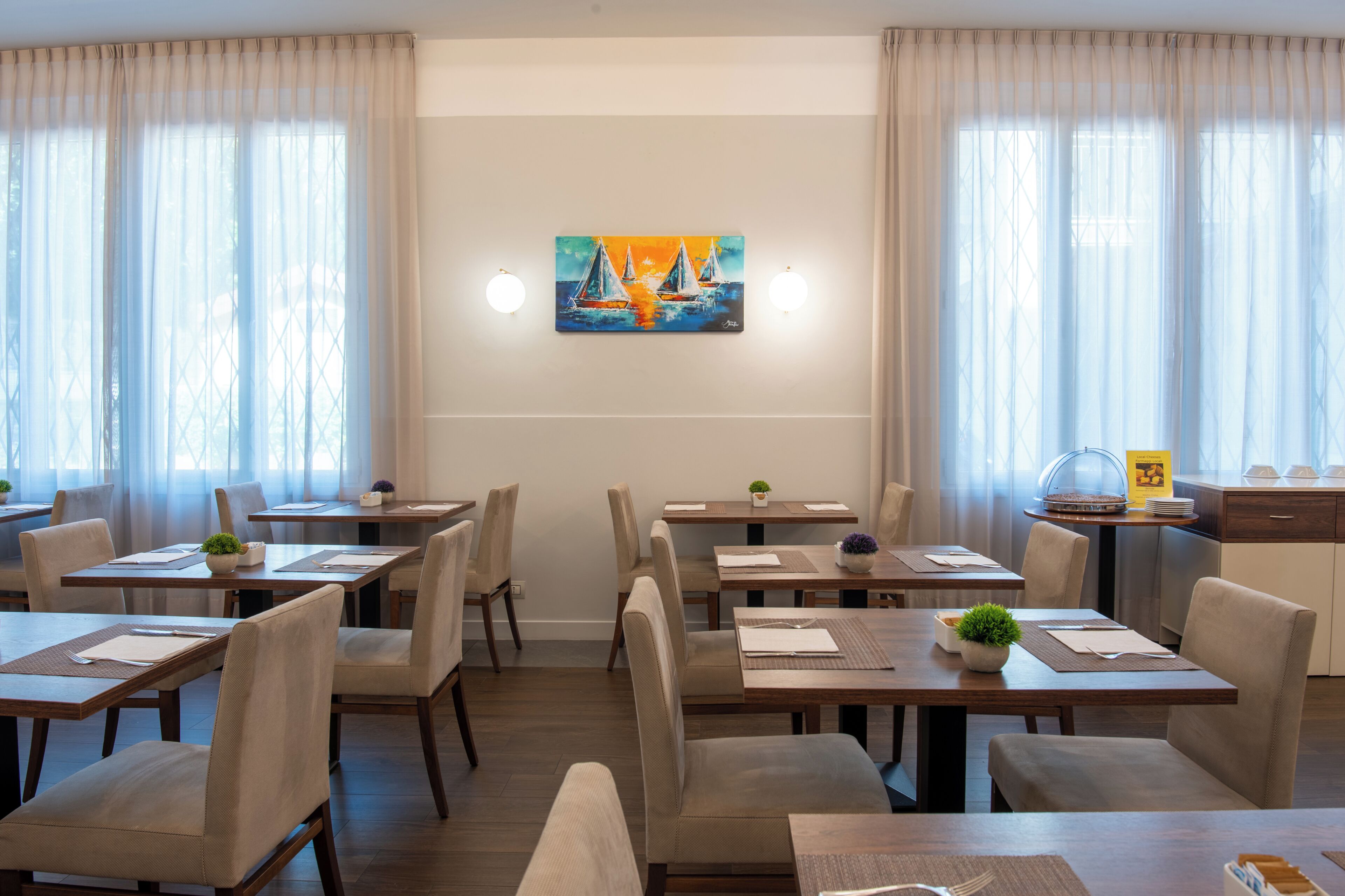 A dining area with tables, chairs, and a painting on the wall.