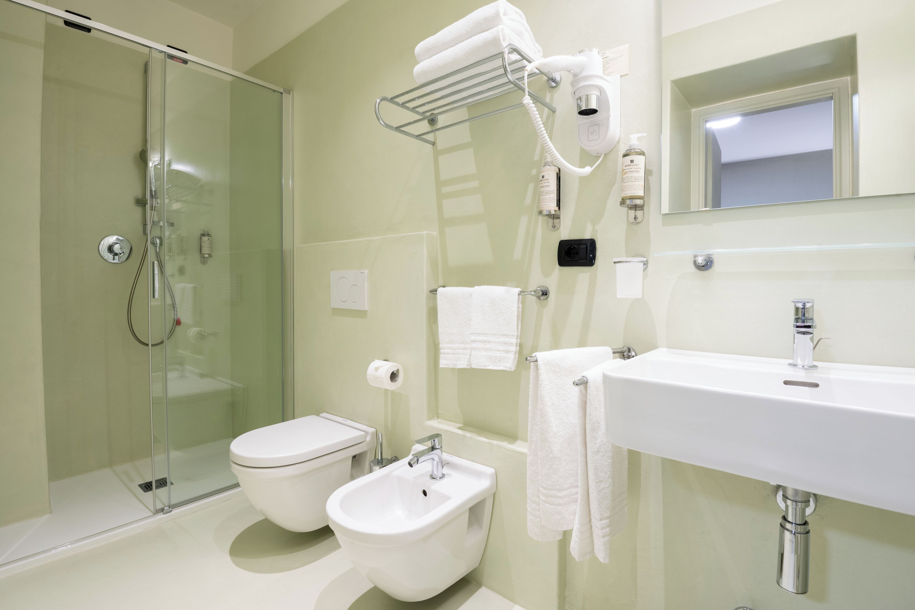 Un bany amb plat de dutxa de vidre, vàter, bidet, rentapousa i assecador.