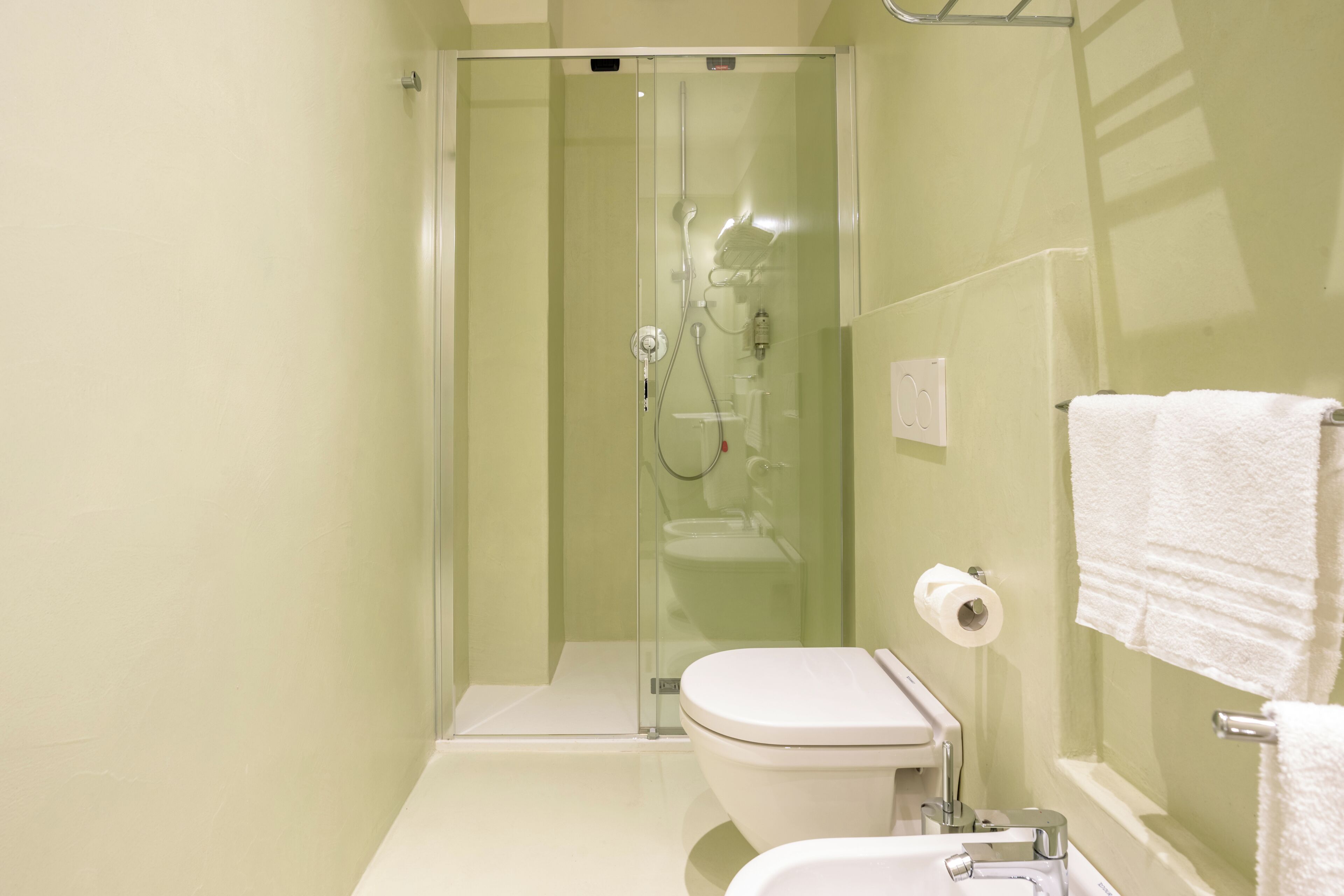 A bathroom with a glass-enclosed shower, a white toilet, and a sink.
