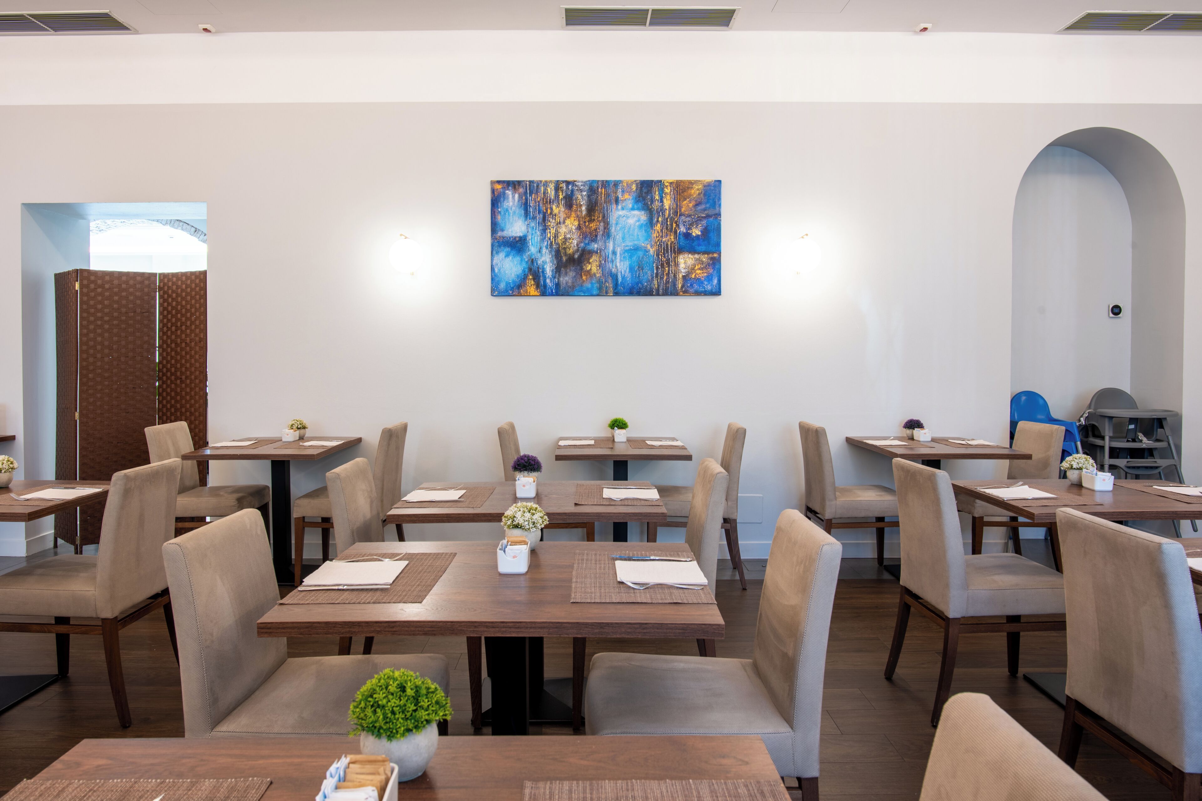 A conference room with tables, chairs, and a large abstract painting on the wall.