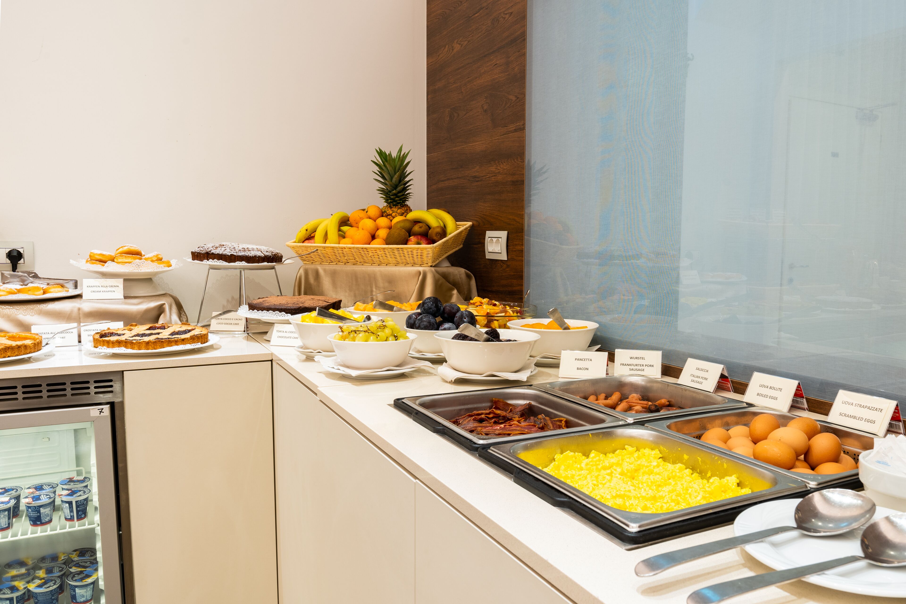Een buffet met diverse gerechten, waaronder fruit, gebak en ontbijtopties.