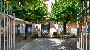 An outdoor café area with tables and chairs, a cobblestone path, and a building with a sign that reads "HOTEL CENTRE". - Hotel Centrale (Cernobbio)