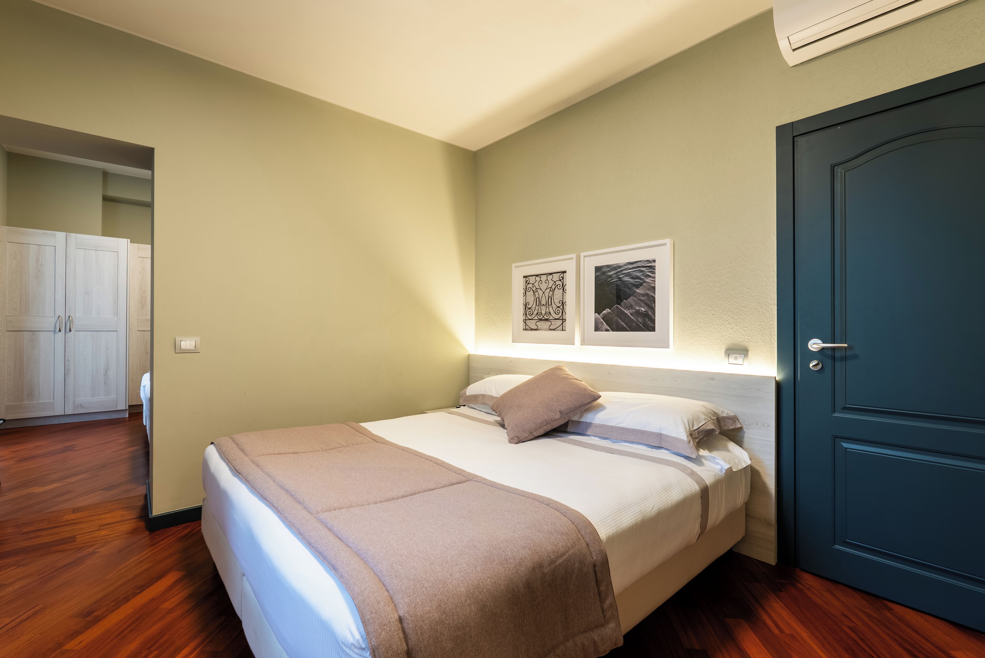 A bedroom with a bed, a wardrobe, and a door.