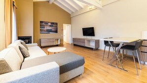A modern living room with a sofa, a dining table, and a TV. - Hotel Centrale (Cernobbio)