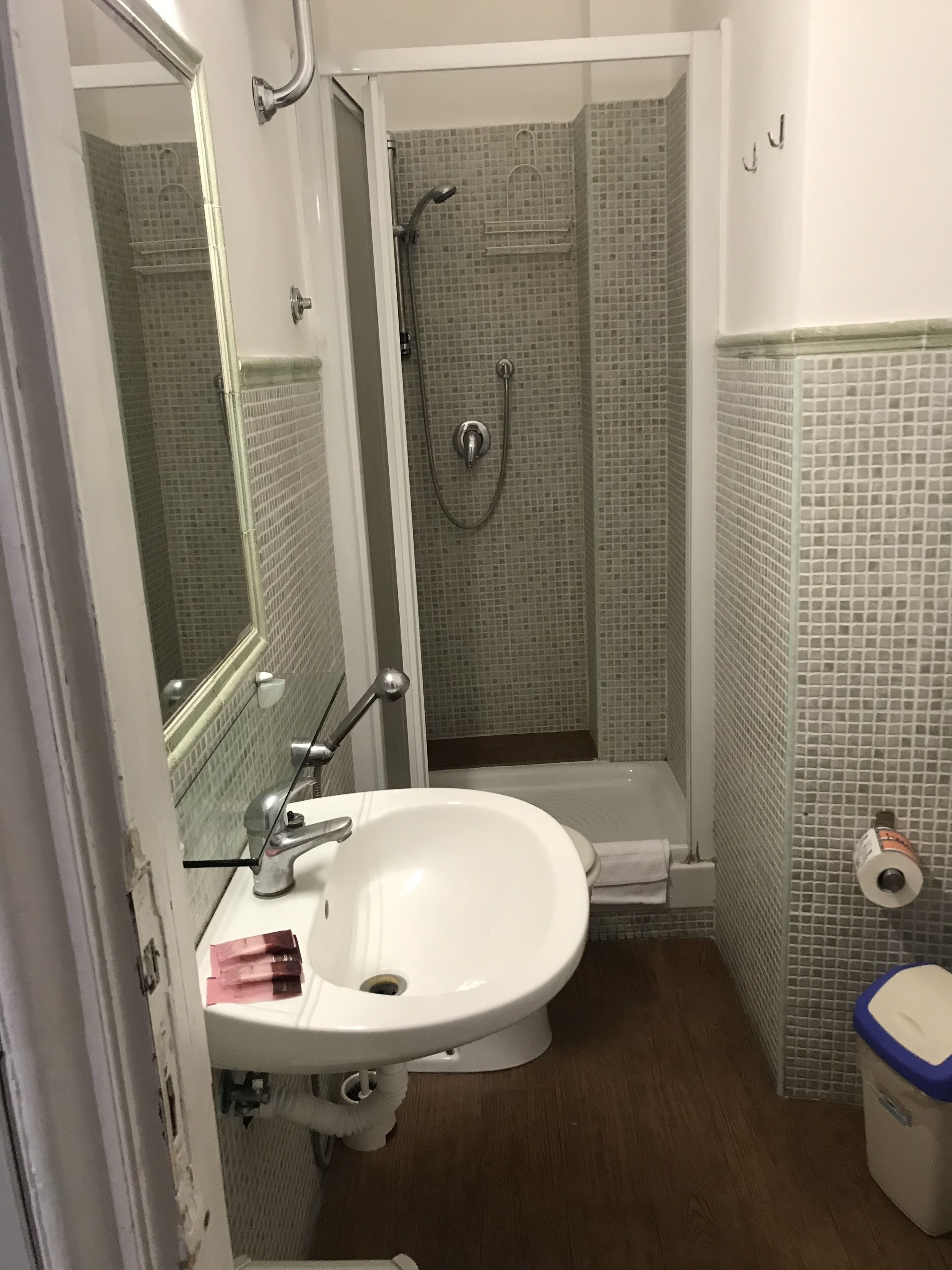 Un bagno con un lavandino bianco, uno spazio doccia in vetro e un water.