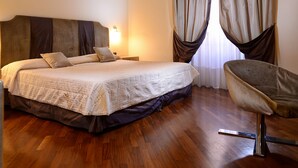 Habitación de hotel con una cama grande, una silla y un techo con diseños intrincados.