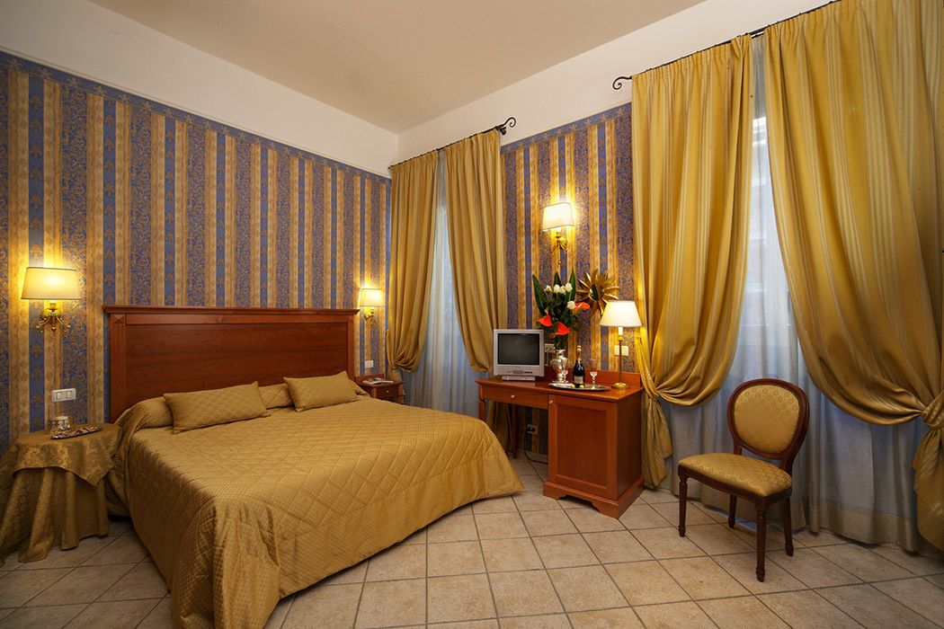Una habitación de hotel con una cama grande, un escritorio con televisión y una silla.